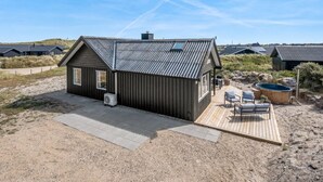 A modern beach house with a deck, outdoor seating, and a hot tub. - "Monna" -  from the sea by Interhome (Hvide Sande)