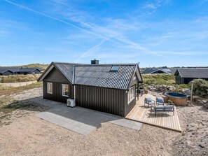 A modern beach house with a deck, outdoor seating, and a hot tub. - "Monna" -  from the sea by Interhome (Hvide Sande)