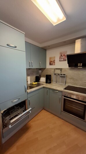Eine Küche mit hellblauen Schränken, einem Edelstahlbackofen, einer Kaffeemaschine und einer Mikrowelle.