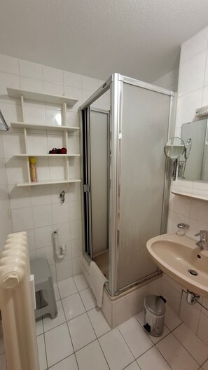 Ein Badezimmer mit Duschkabine, Waschbecken, Toilette und Ablageflächen.
