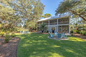 A two-story house with a covered porch, surrounded by a well-maintained lawn and trees. - Seafarer Lodge South (Jekyll Island)