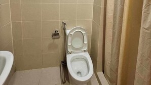 A small bathroom with a toilet, a shower curtain, and a towel rack. - GRASS Residences SM NORTH QC Staycation (Quezon City)