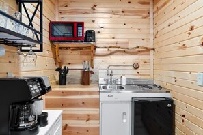 A compact kitchen with a microwave, toaster, sink, and coffee maker.
