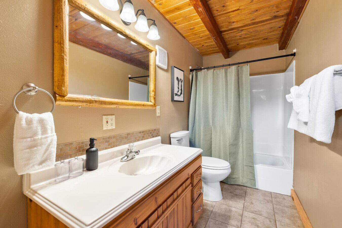 Un baño con tocador de madera, un espejo grande, cortina de ducha y un inodoro.