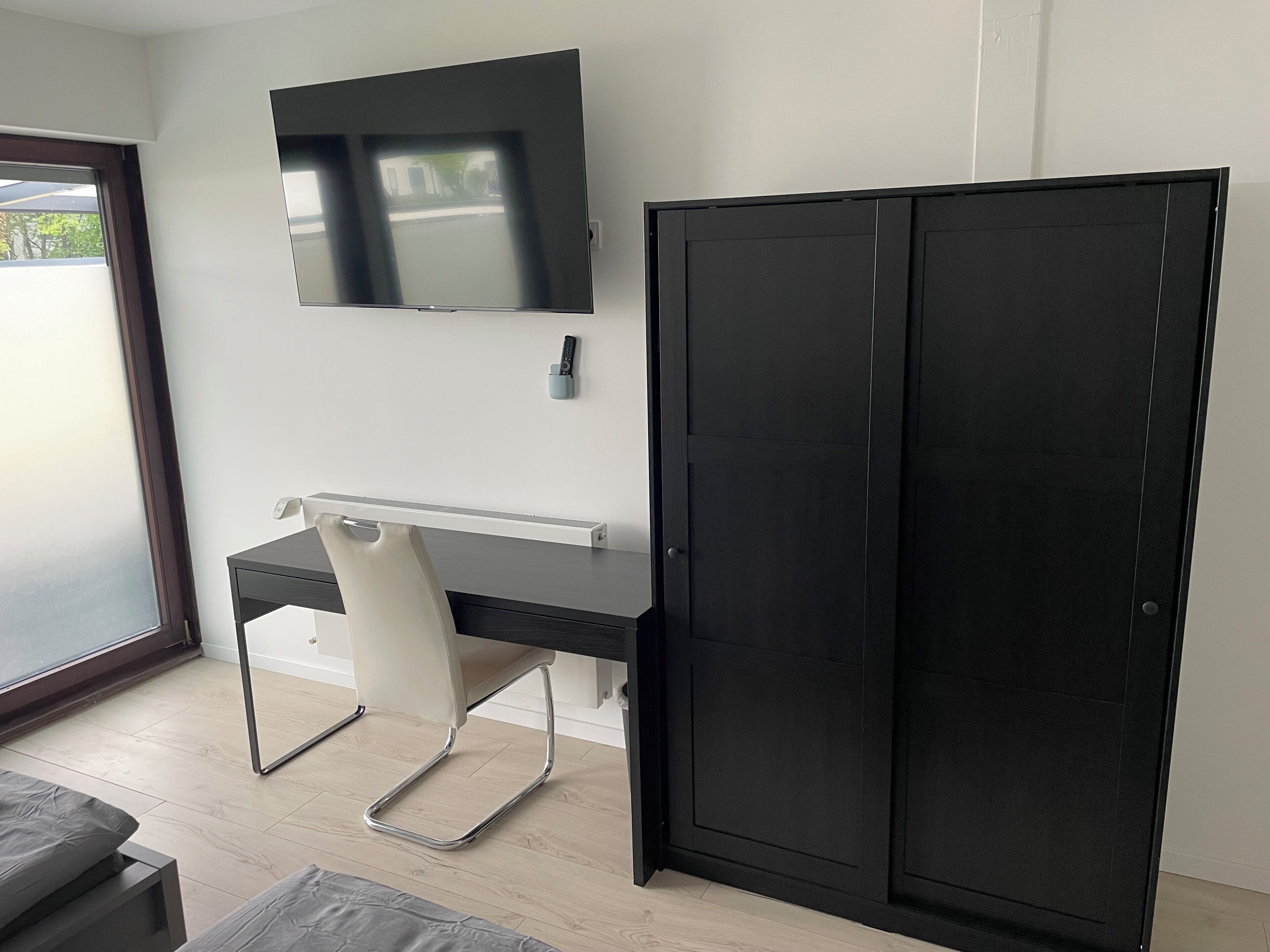 Une chambre moderne équipée d’un bureau, d’une chaise et d’une armoire noire.
