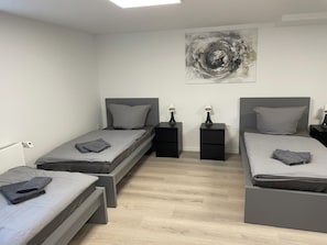 A modern bedroom with two single beds, bedside tables, and a large abstract painting on the wall. - Blauer Stein - Pure - bl07-haus (Pulheim)