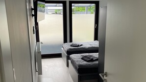 A narrow hallway leading to a bedroom with a bed and a TV mounted on the wall. - Blauer Stein - Pure - bl07-haus (Pulheim)