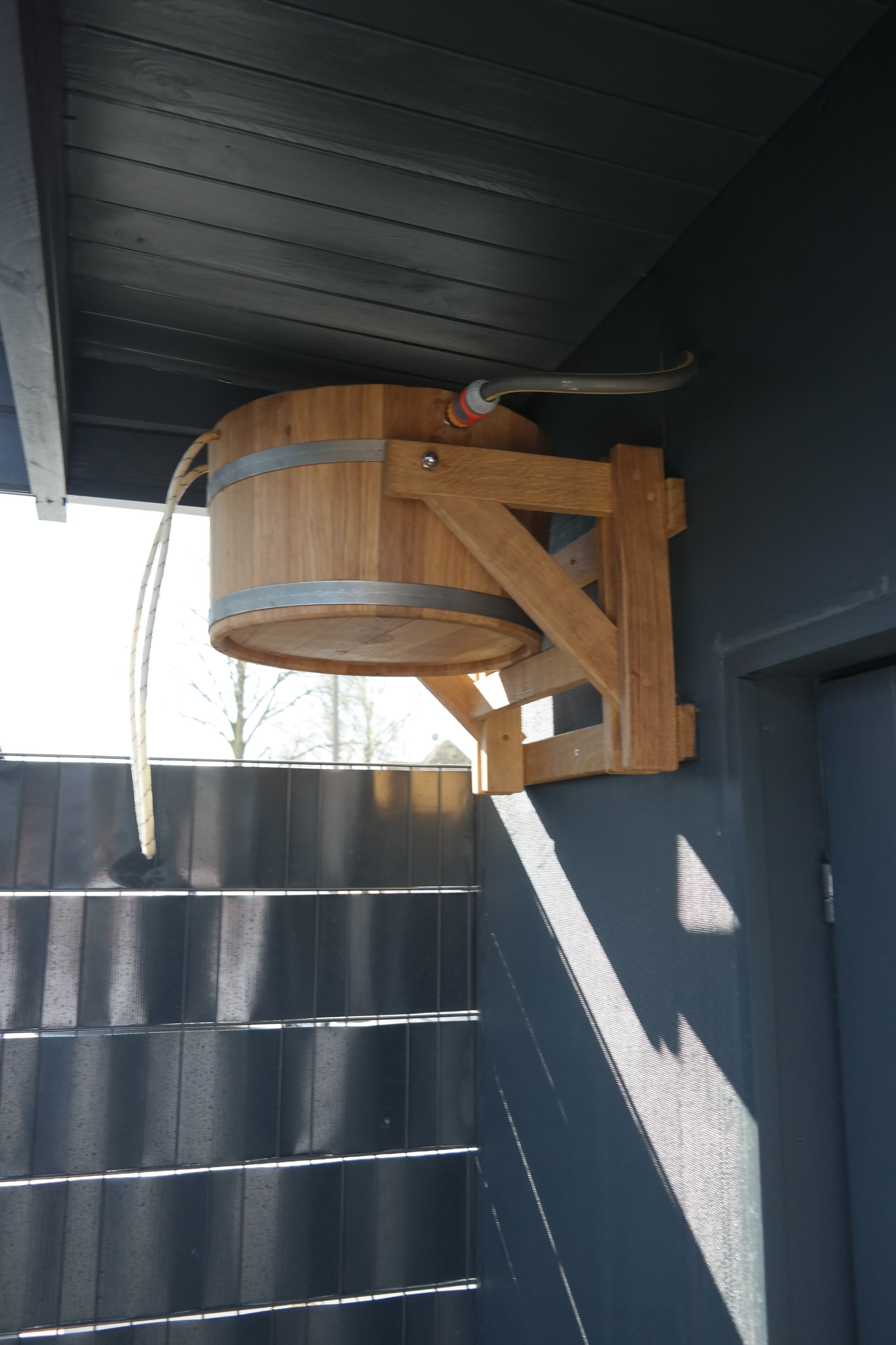 A wooden barrel structure attached to a building's exterior wall.