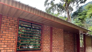 A brick building with a metal-framed window and a red roof. - Country House in Tingo Maria - Adelaide Resort (Tingo María)