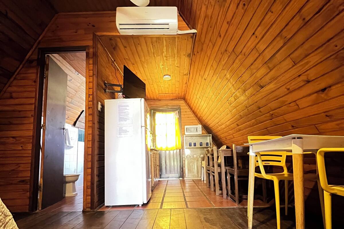 Un intérieur en bois avec un ventilateur de plafond, un réfrigérateur blanc, un four à micro-ondes et une table à manger avec des chaises.
