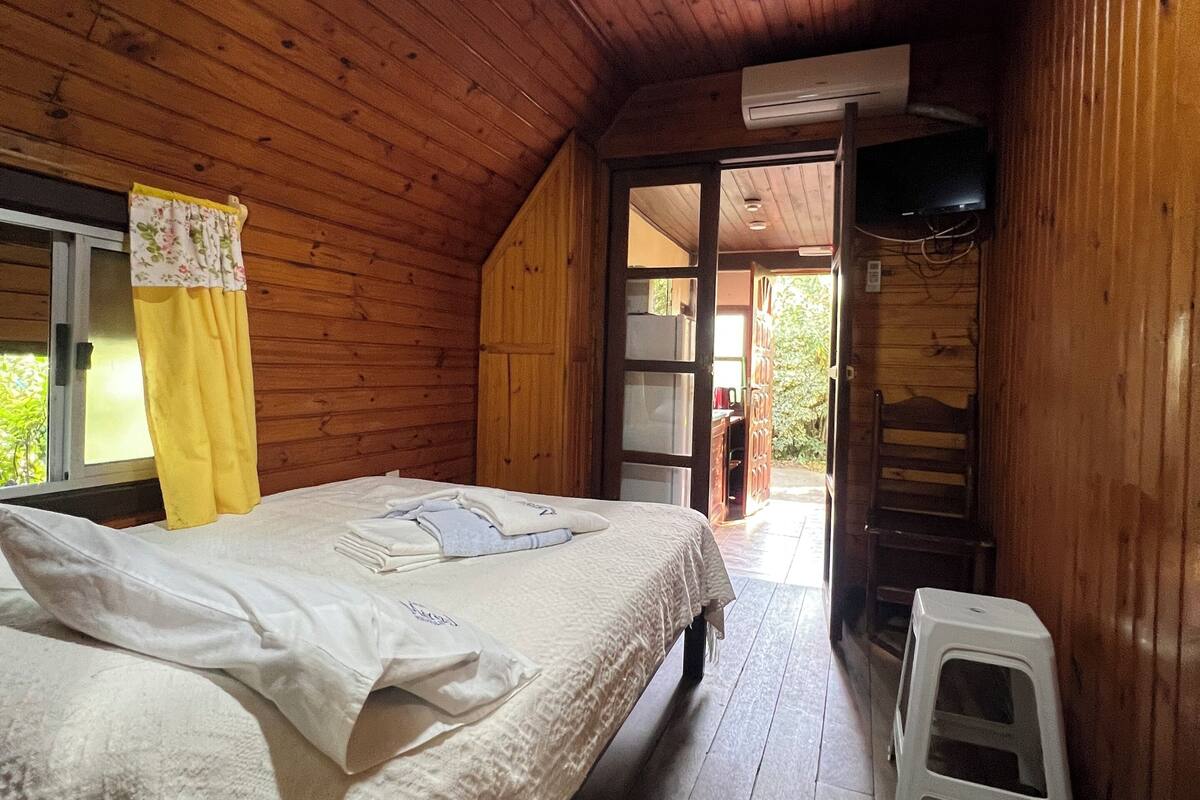 Une pièce de cabane en bois comprenant un lit, un petit tabouret et un téléviseur.