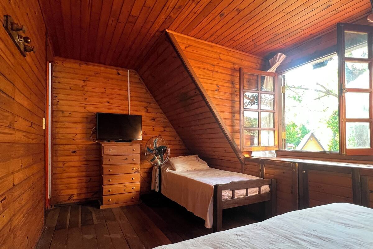 Une chambre dans une cabane en bois, avec un lit, une commode et un téléviseur.