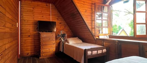 Un dormitorio de cabaña de madera con cama, cómoda y televisor.