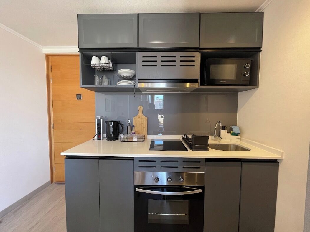 A compact kitchen with a microwave, oven, and sink.