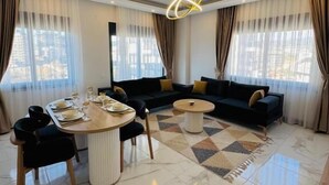 Una sala de estar moderna con comedor, que incluye un conjunto de sofás, una mesa de centro y una mesa de comedor con sillas.