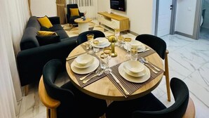 Un comedor con una mesa redonda para cuatro personas, un sofá, un televisor y un extintor.