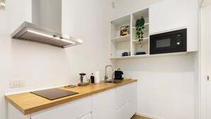 Eine moderne Küche mit weißen Schränken, einer Holz Arbeitsplatte, einer eingebauten Mikrowelle und einer Edelstahl-Dunstabzugshaube.