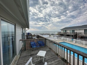 Eine Holzterrasse mit Pool, Liegestühlen und Blick auf den Ozean.