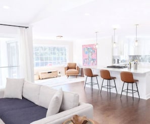 A modern living room with a sofa, a coffee table, and a kitchen area with bar stools. - Inside the Perimeter|Spacious-Fenced|Extended Stay (Atlanta)
