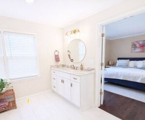 A bathroom with a white vanity, a large mirror, and a window with blinds. - Inside the Perimeter|Spacious-Fenced|Extended Stay (Atlanta)