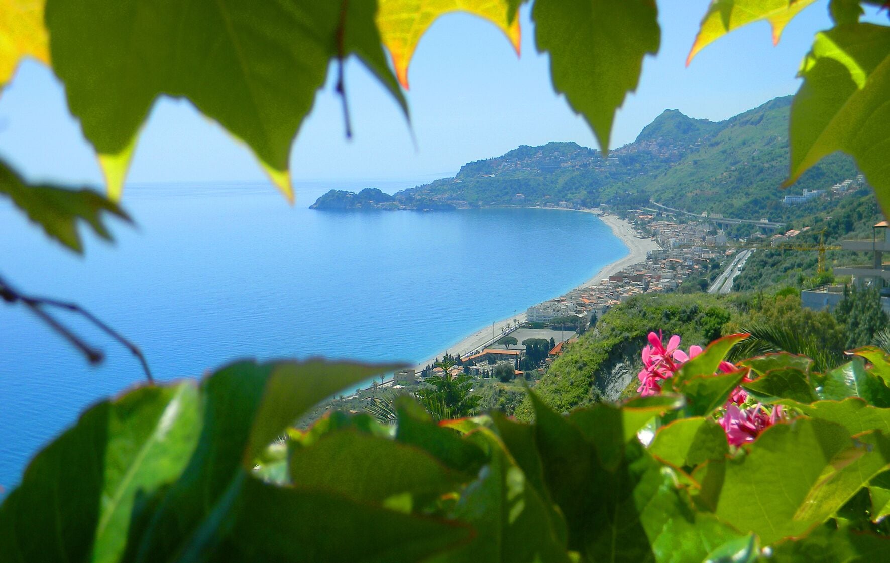 A coastal town with a beach, buildings, and greenery.
