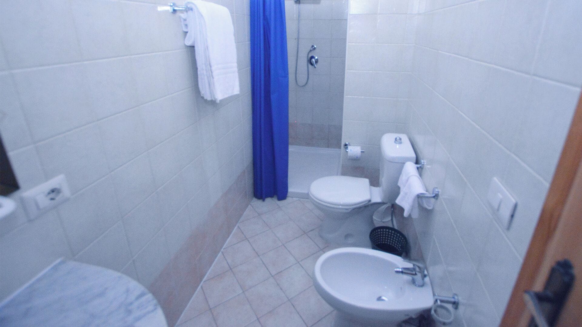 Un baño pequeño con azulejos, un inodoro, lavamanos y ducha.