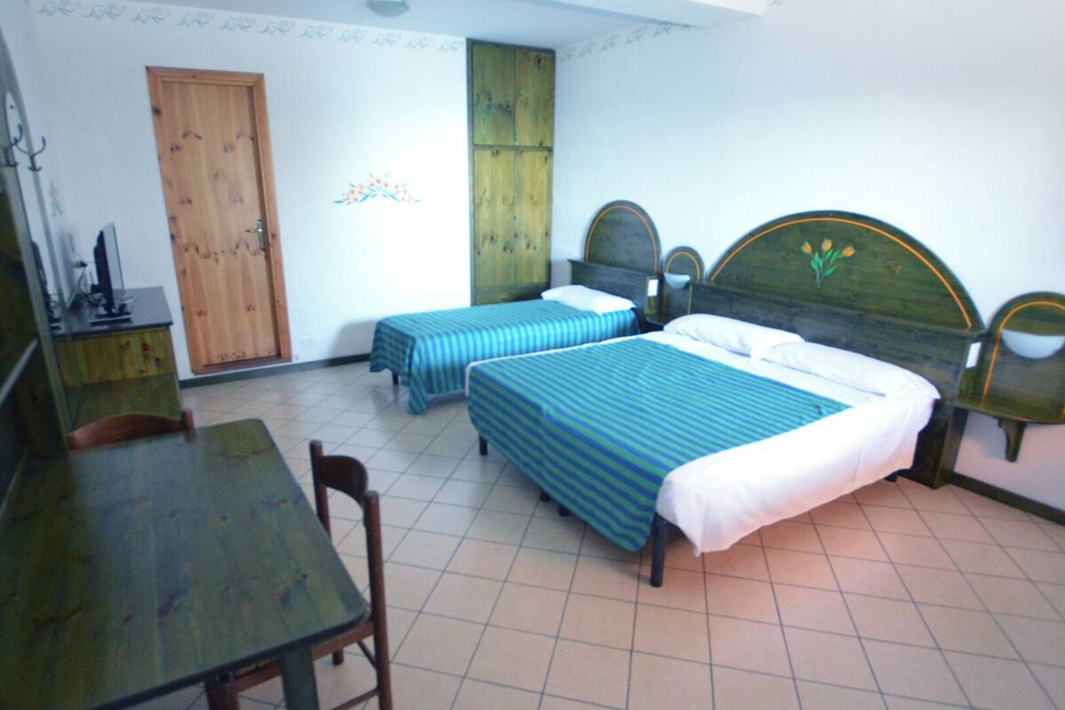 A room with two single beds, a desk, a chair, a wardrobe, and a mirror.