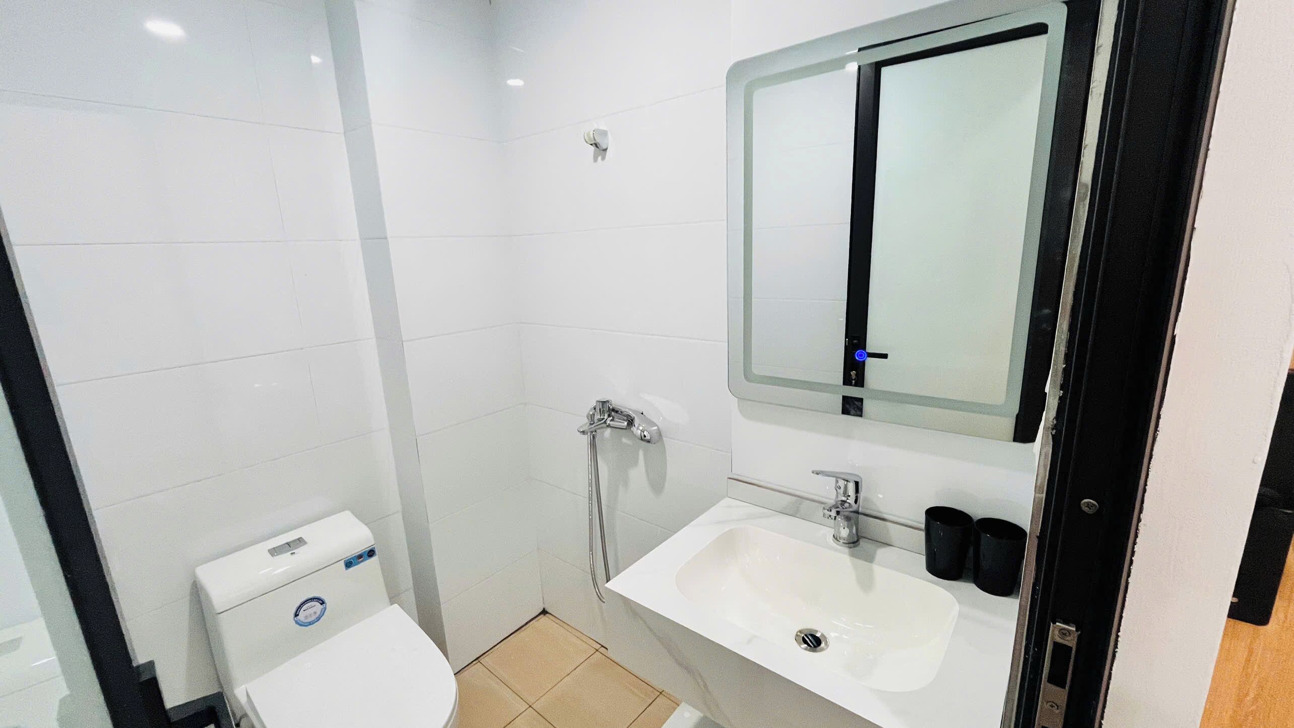A small, modern bathroom with a toilet, a shower, and a sink.
