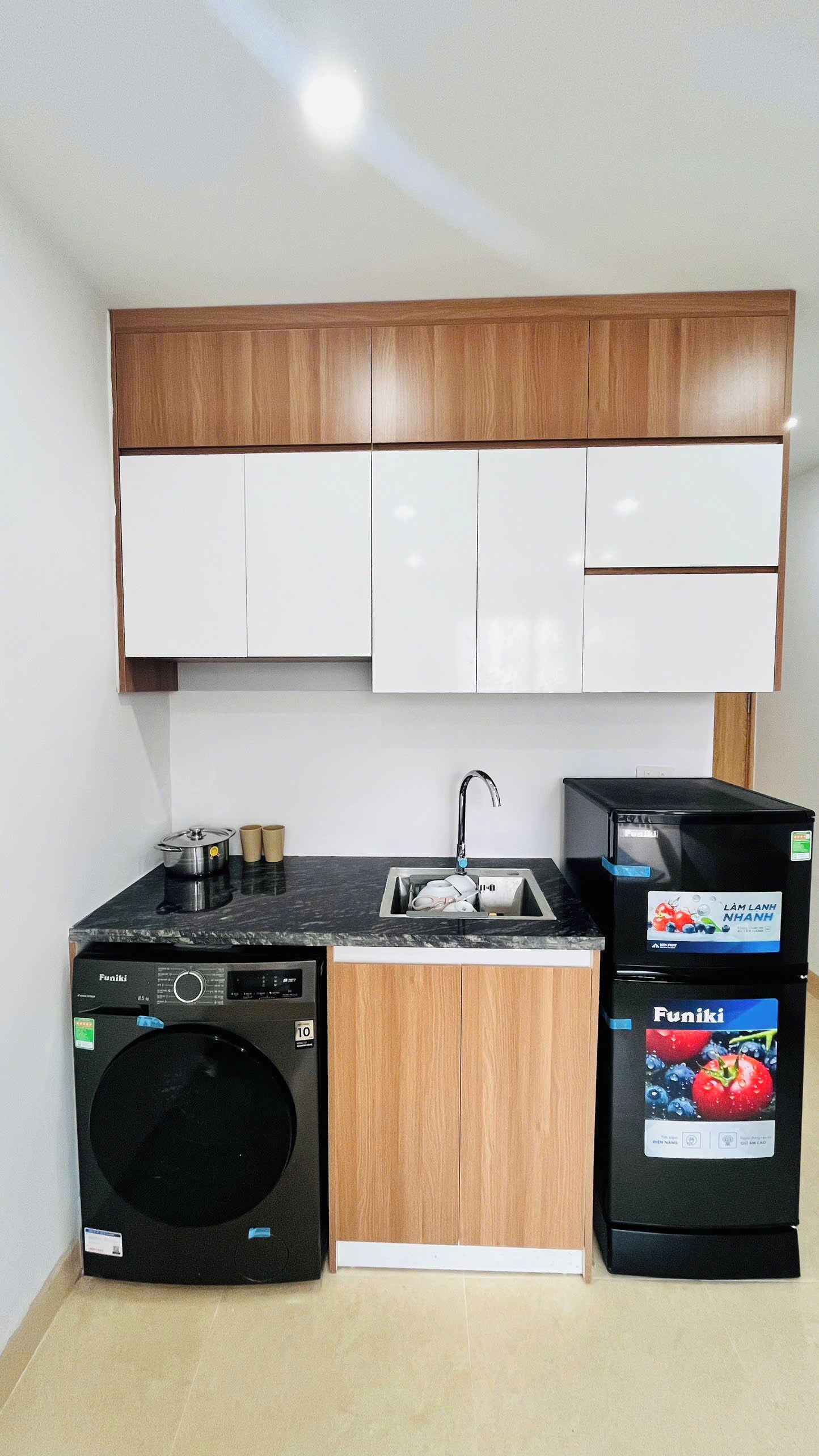 Een kleine keuken met een wasmachine, een koelkast en een spoelbak.