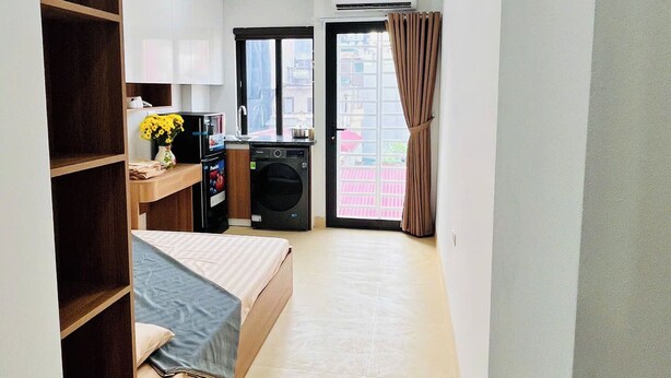 A compact room with a bed, a kitchenette, and a small window.