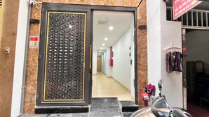 A hotel entrance with a decorative metal gate, a hallway leading inside, and a motorcycle parked outside.