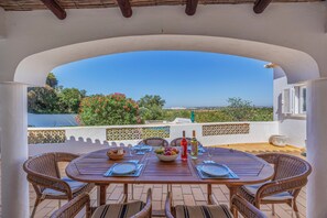 An outdoor dining area with a view of the city, wicker furniture, and a table set for two. - Casa Belcarina: Fantastic luxury villa with ocean views in Quinta Da Saudade, Guia, Albufeira   (Albufeira)