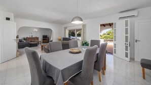 Un espace repas moderne avec une table dressée pour six personnes, entourée de chaises grises recouvertes de tissu.