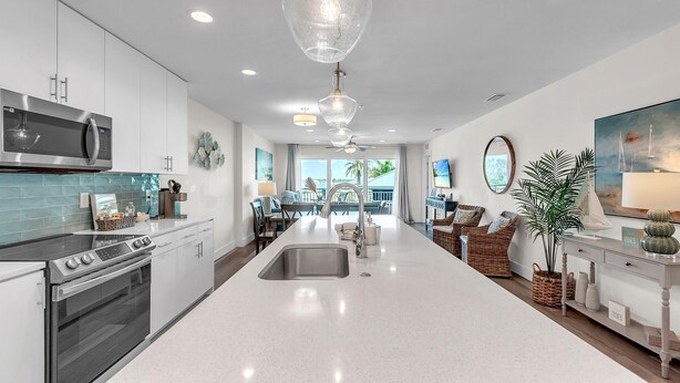 A modern kitchen with a central island, stainless steel appliances, and a view to the dining area. - Madeira Del Mar 302 (Madeira Beach)