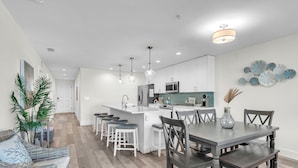 A modern kitchen with white cabinetry, a central island, and pendant lighting. - Madeira Del Mar 302 (Madeira Beach)