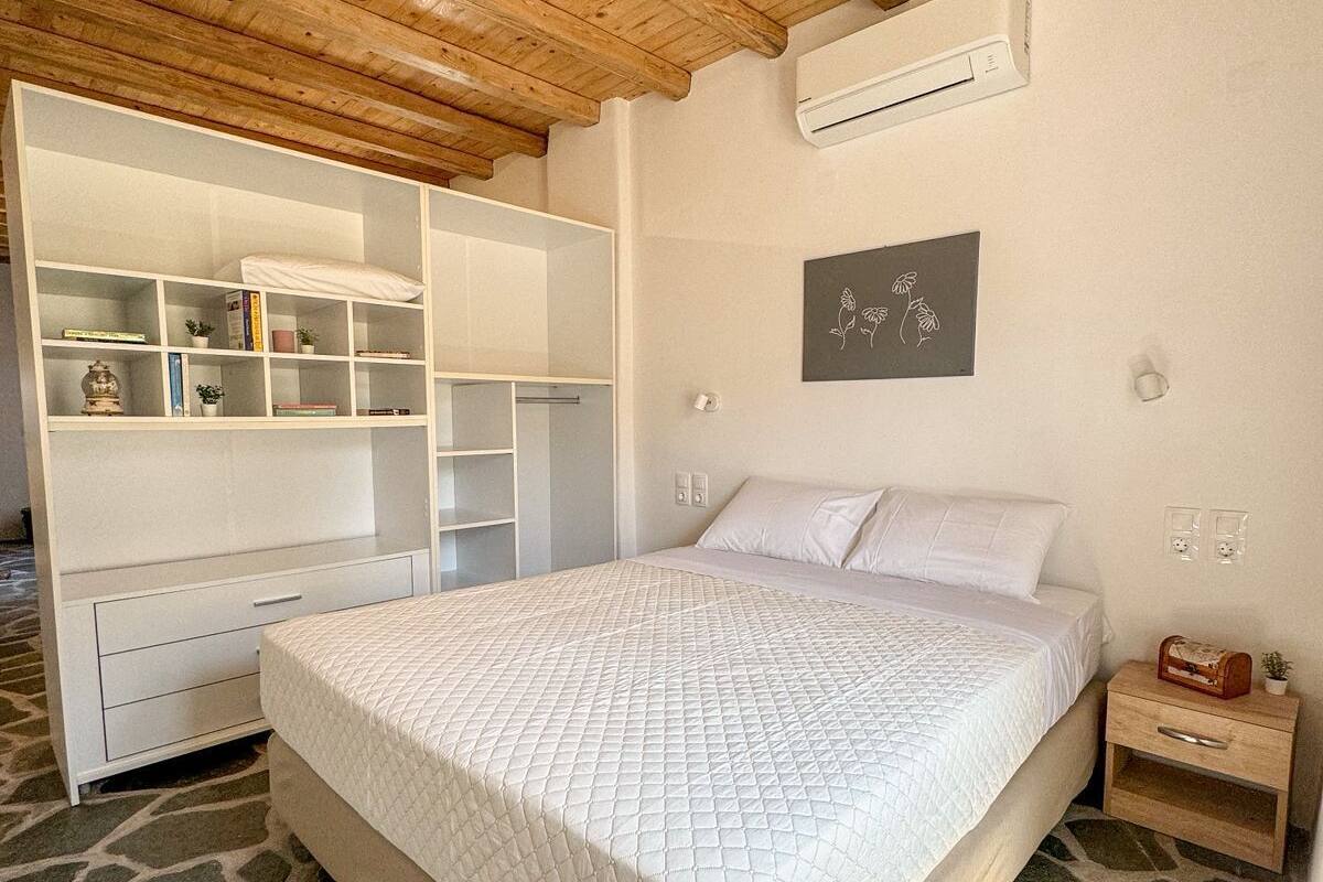 A bedroom with a large bed, built-in wardrobe, and a stone-patterned floor.