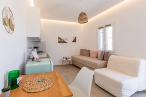 Ein modernes Wohnzimmer mit Sofa, Esstisch und einer Küchenzeile.
