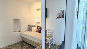 Un dormitorio con cama, una silla, un espejo y suelo de diseño de piedra.
