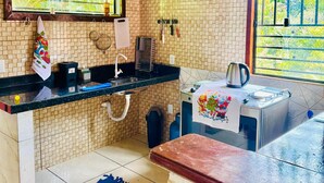 Una cocina con salpicadero de azulejos, una ventana con vistas, un lavabo, una estufa y una alfombra azul en el suelo.