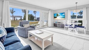 Ein modernes Wohnzimmer mit Sofa, Couchtisch, Fernseher und Essbereich mit Stühlen und Tisch.