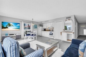 Ein modernes Wohnzimmer mit Fernseher, Sofa und Essbereich.