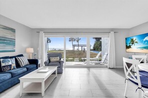 Ein Wohnzimmer mit blauem Sofa, gestreiftem Sessel, weißem Couchtisch und Fernseher.