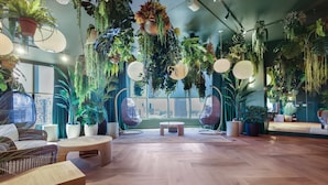 A room with a wooden floor, wicker furniture, hanging plants, and large windows. - 501 First Luxury 1 BR + Den & 2 Baths Rooftop Pool & GYM 402 (Miami)