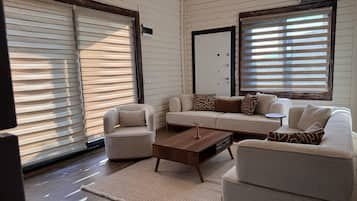 A living room with a sofa, armchairs, a coffee table, and a rug.