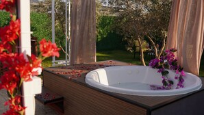 A hot tub with a wooden deck, surrounded by greenery and flowers. - ON2 Bungalov Villas (Dosemealti)