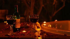 A table with a bottle of wine, two glasses of red wine, and a candle. - ON2 Bungalov Villas (Dosemealti)