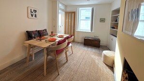 A dining area with a table set for four, a sofa, a wooden chest, and a fireplace. - Beautifully Presented Cosy Home in Kirkcudbright - Pass the Keys (Kirkcudbright)