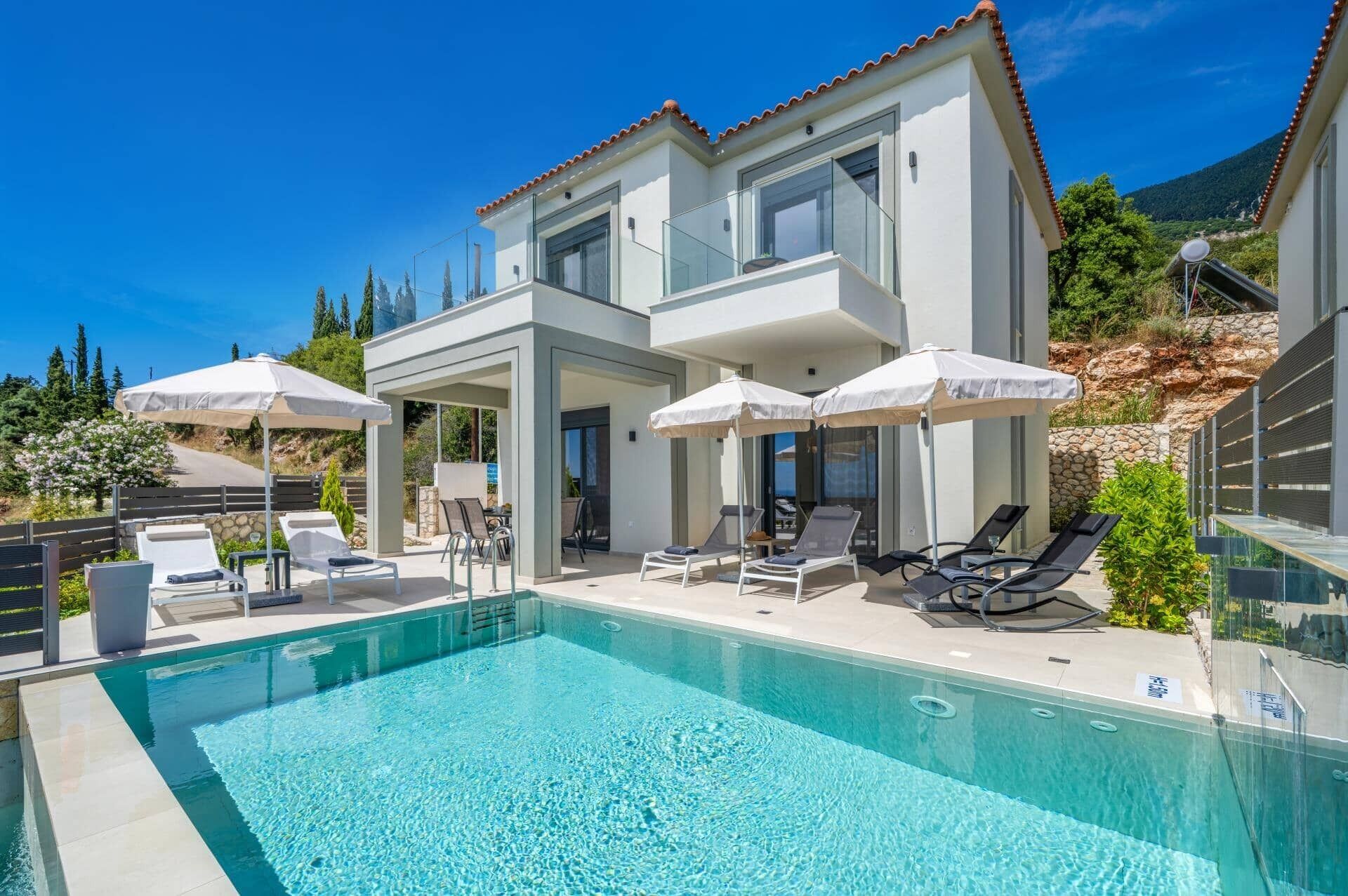 Ein modernes, zweistöckiges Gebäude mit Pool, Liegestühlen und Sonnenschirmen.