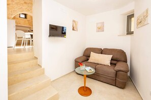 A living room with a brown sofa, a glass coffee table, and a staircase leading to another room. - Villa Trullo Desideri by Villa Plus (Casalini)