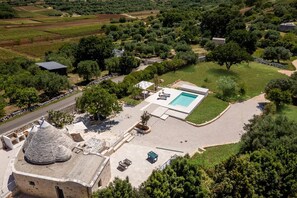 An aerial view of a property with a swimming pool, outdoor seating, and a stone structure. - Villa Trullo Desideri by Villa Plus (Casalini)